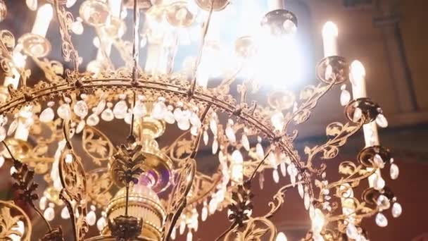 Ortodoxa, cristianismo, igreja. Feixe de luz brilha sobre o velho lustre gondel com velas penduradas no topo do teto alto com arte — Vídeo de Stock