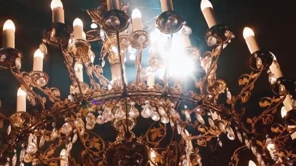 Православие, христианство, церковь. Луч света сияет над старой гондельской люстрой со свечами, свисающими с вершины высокого потолка с искусством — стоковое видео
