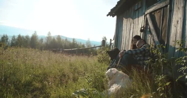 Mountain country lovestory. 4k. Man and woman enjoy evening lights sitting on the porch with their two dogs - Do bermann and Labrador Retriever — Stock Video