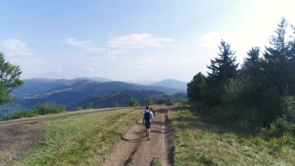 Вид з повітря. 4k. Чоловік з рюкзаком ходить по гірській дорозі в сонячний день. Покликання — стокове відео