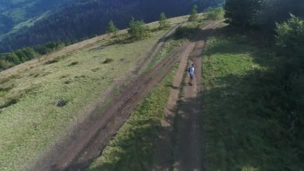 Vista aérea. 4k. El hombre con una mochila camina por el camino de la montaña en un día soleado. Vocación — Vídeos de Stock