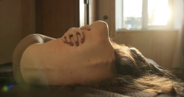 Joven mujer deprimida con el pelo largo y oscuro yace en la cama ante un espejo y se rasca. Concepto de enfermedad. 4k — Vídeos de Stock