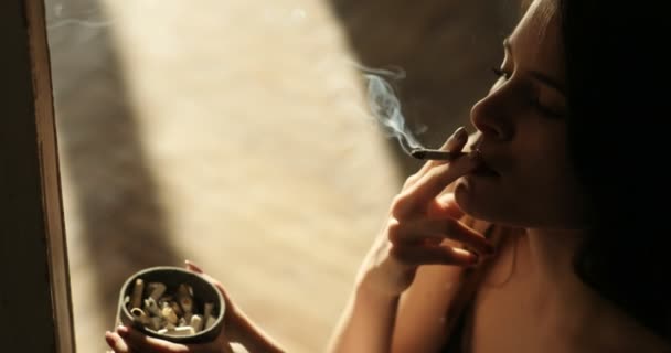 Mulher deprimida. Menina com cabelos longos morena fuma um charuto sentado no chão interior nas luzes da noite. 4k — Vídeo de Stock