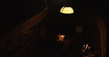 11. yüzyılın eski kütüğü kulübesinde karanlık oda. Mum ışığı. Yaşlı adam, Monk, Chronicler, siyah bornozu giymiş, Hood 'da. 4k video. Mum