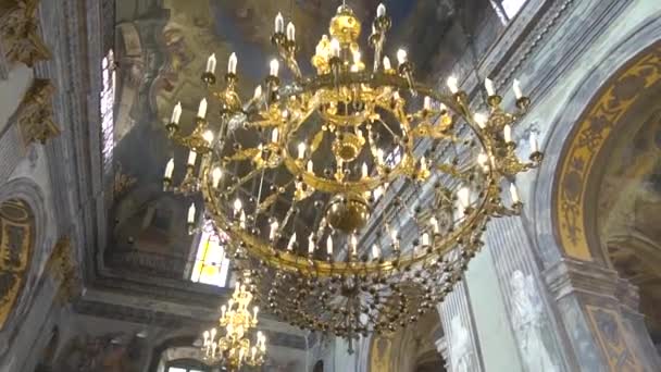 Żyrandol w kościele. Świece są zapalane na żyrandol w Kościele Prawosławnym. w tle, duży ikonostas. Zewnątrz wieczorem. — Wideo stockowe