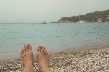 Kadın ayakları üzerinde deniz kıyısı. Dağ ve shi ufukta