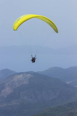 Dağların üzerinden uçan bir adam bir paraşüt içinde. Parasailin