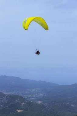 Dağların üzerinden uçan bir adam bir paraşüt içinde. Parasailin