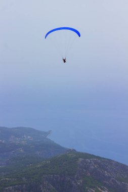 Dağların üzerinden uçan bir adam bir paraşüt içinde. Parasailing