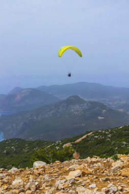 Dağların üzerinden uçan bir adam bir paraşüt içinde. Parasailin