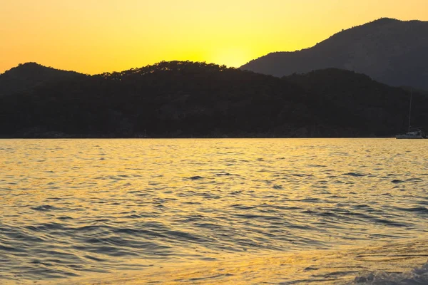 Akdeniz manzara. Günbatımı parlak akan ile denizde bulutların arasından güneş ışınlarının renkli. Dağları'nın siluetleri. Adam
