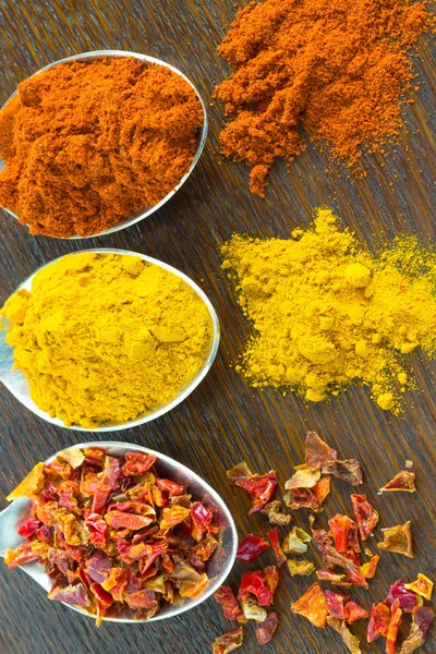 Kaşık üzerinde zemin baharatlar: kırmızı biber, zerdeçal ve yaprakları kırmızı biber masada