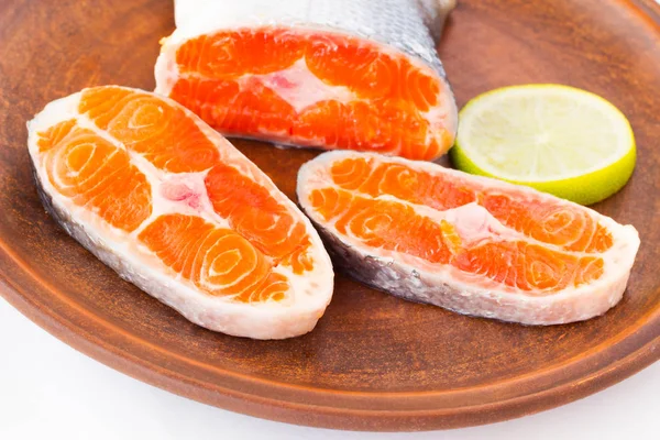 Sliced salmon and a slice of lemon on a ceramic plate. Close up. Top view