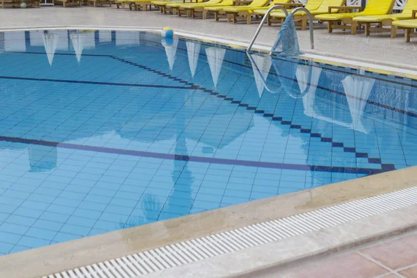 Part of the outdoor swimming pool at the hotel, the ball in the corner of the pool, around the yellow sunbed