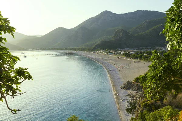 Sahilde günbatımı, etrafı dağlarla çevrili, Sahilde şezlong vardır