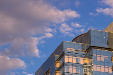 Beton ve camdan modern bir binada. Bulutların üstünde gökdelenler yansıması