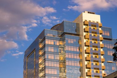 Beton ve camdan modern bir binada. Bulutların üstünde gökdelenler yansıması