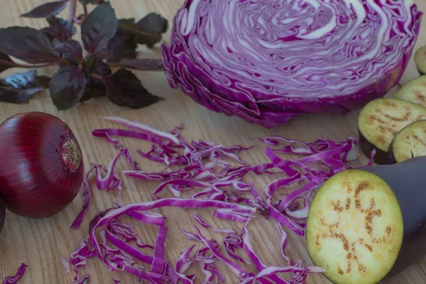 Sliced eggplant, purple onion and sliced purple cabbage on the tabl