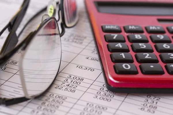 Business concept: the table with the calculations, calculator and glasses. Close-up