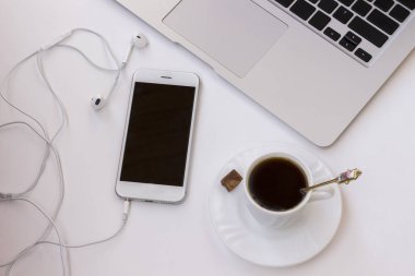 İş kavramı: telefon kulaklık, bir fincan kahve ve bir pasta masanın üzerinde. Yakın çekim. Üstten görünüm