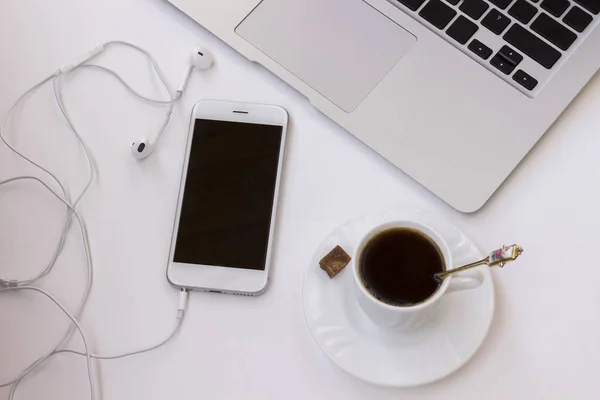 stock image Business concept: phone with headphones, a cup of coffee and a cake on the table. Close-up. Top view