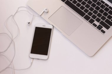 Dizüstü bilgisayar ve telefon masada kulaklıklarla. Yakın çekim. Üstten görünüm