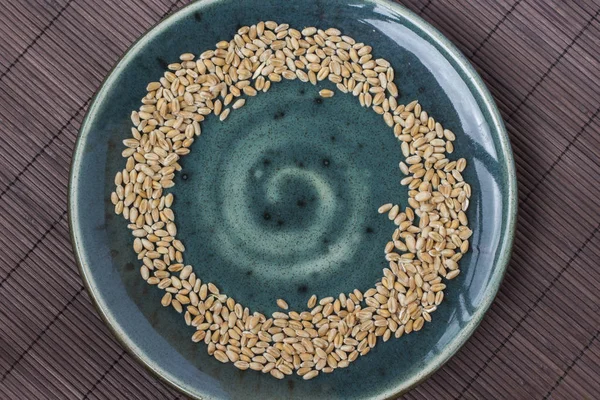 在绿色陶瓷板上的小麦颗粒 棕色背景 顶部视图 — 图库照片