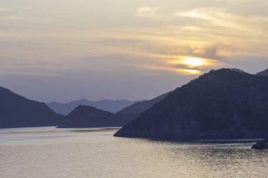 Deniz kıyısında günbatımı. Ufuktaki dağlar