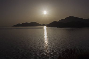 Günbatımı denize. Deniz yüzeyi güneş yolda yansımasıdır. Ufukta - dağlar