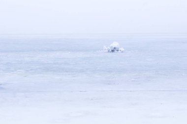 Bir parça kar donmuş nehrin arasında. Sisli