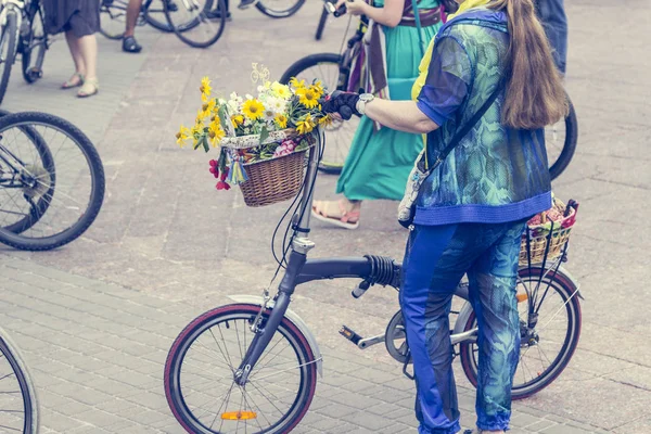 Rowery z koszykami kwiatów. Kobiety w jasnych ubrań trzymać kierownice — Zdjęcie stockowe