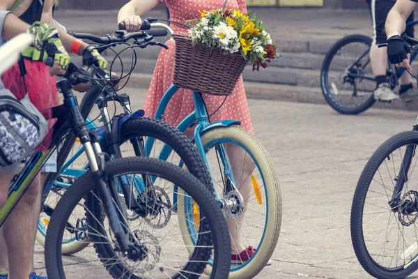 Rowery z koszykami kwiatów. Kobiety w jasnych ubrań trzymać kierownicy — Zdjęcie stockowe