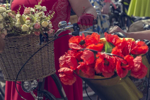 Bicicletas com cestas de flores. Mulher de saia vermelha segura o guidão — Fotografia de Stock