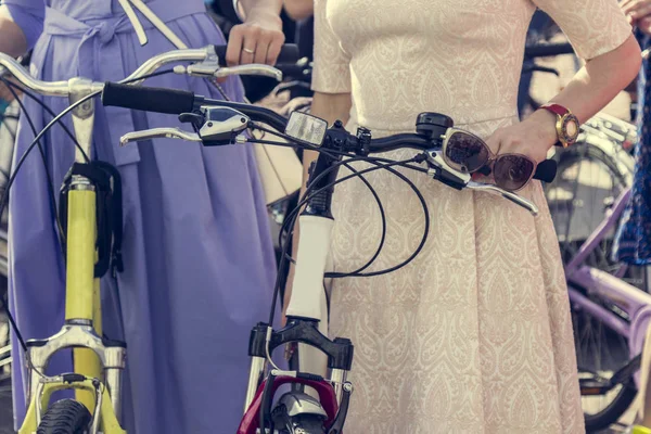 Koncepcja: kobiety na rowery. Kobieta w jasne ubrania trzymać kierownicy. Część obrazu — Zdjęcie stockowe