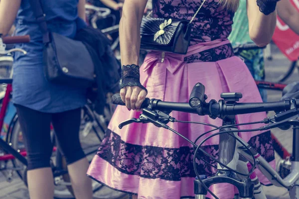 Koncepció: nők kerékpáron. A kormányt tartó kezek. Rózsaszín szoknya, fekete csipkével — Stock Fotó