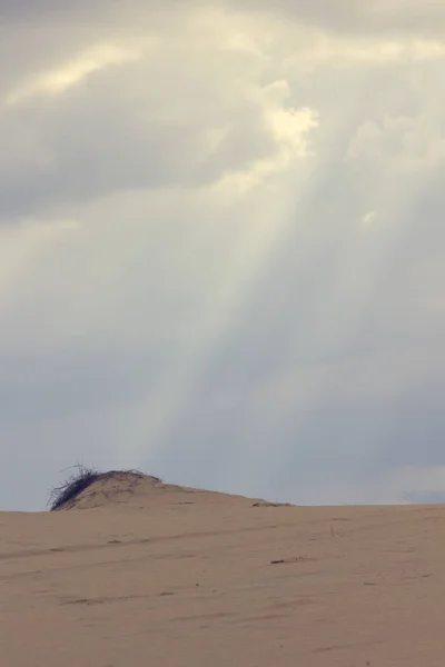 De zonnestralen door de wolken schijnen op de zandduin — Stockfoto