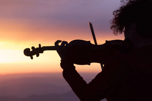 Silhouette of a woman with a violin at sunset