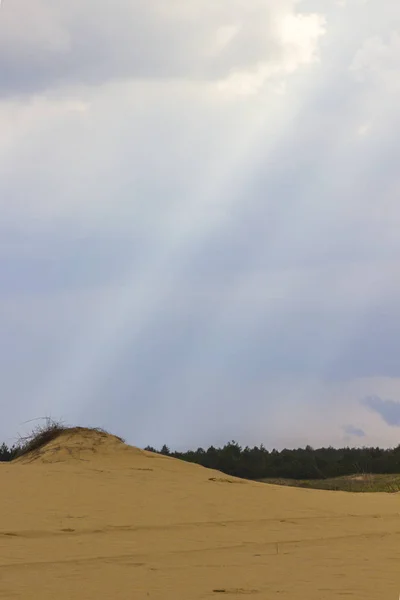 De zonnestralen door de wolken schijnen op de zandduin — Stockfoto