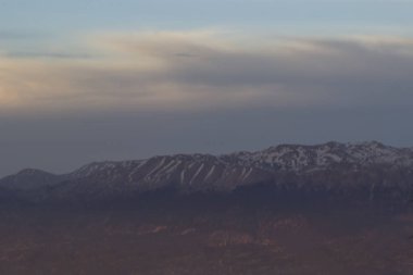 Dağlarda güneşbalan pembe gün batımı, dağların tepesinde kar yatıyor