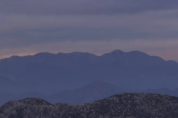 Pink sunset  in the mountains, on the tops of the mountains lies snow