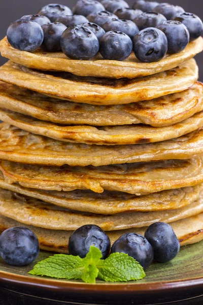 Delicious pancake with blueberries in a green dish on black table