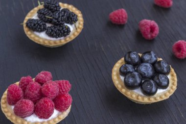 Ahududu, yaban mersini ve böğürtlen li sepet şeklinde kurabiyeler. Ahşap arka plan