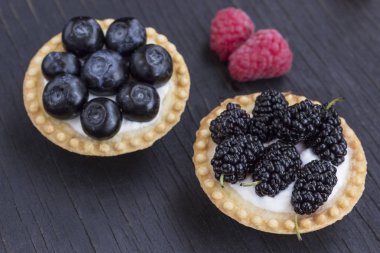 Ahududu, yaban mersini ve böğürtlen li sepet şeklinde kurabiyeler. Ahşap arka plan