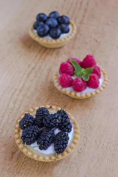 Galletas en forma de canasta con frambuesas, arándanos y moras. Fondo de madera — Foto de Stock