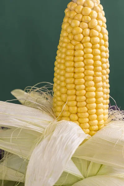 Raw corn on the cob with green leaves and corn stigmas