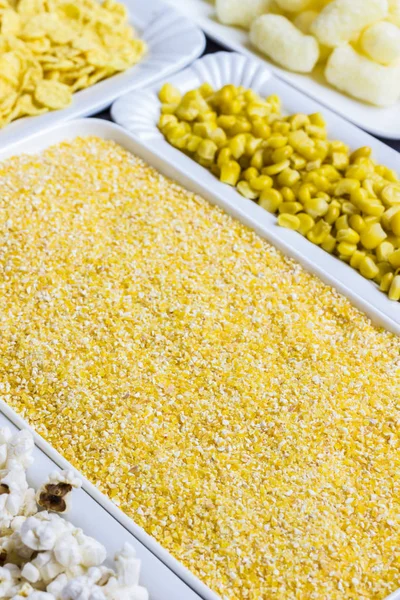 Cornmeal, corn sticks and flakes in white plates, top view