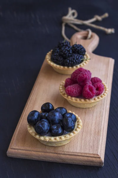 Biscoitos em forma de cesta com framboesa, mirtilo e amoras. Fundo preto — Fotografia de Stock