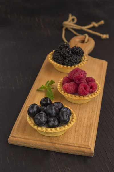 Biscoitos em forma de cesta com framboesa, mirtilo e amoras. Fundo preto — Fotografia de Stock