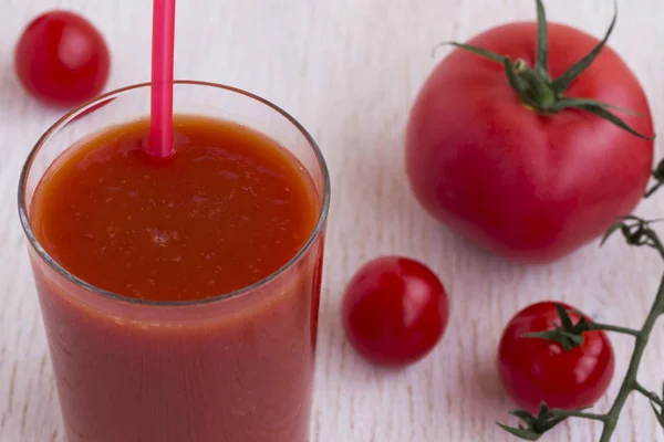Beyaz bir arka plan üzerinde domates suyu ve kırmızı domates bir bardak — Stok fotoğraf