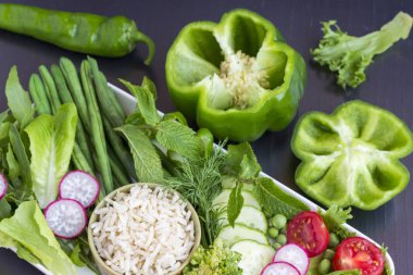 Pirinç ve yumurta ile sebze bir dizi: bezelye, kuşkonmaz, turp, brokoli, marul, domates. Siyah arka plan